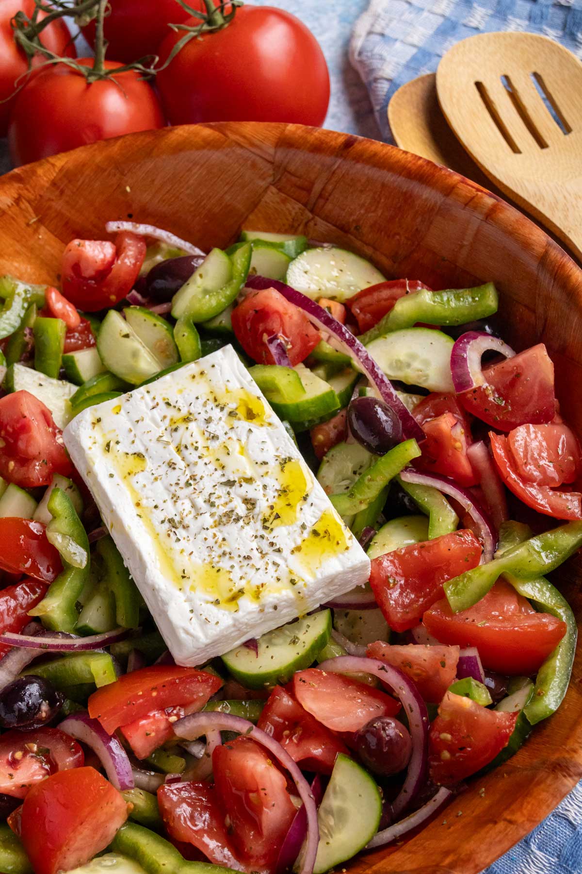 A serving bowl of horiatiki (Greek salad) topped with a slab of feta cheese.