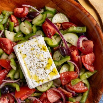Authentic Greek salad (horiatiki) topped with a slab of feta cheese.