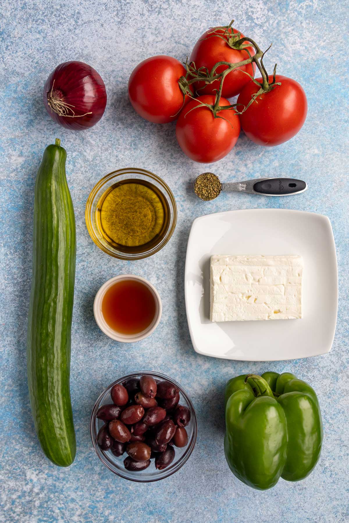 Ingredients for horiatiki (Greek salad) on a light blue background.