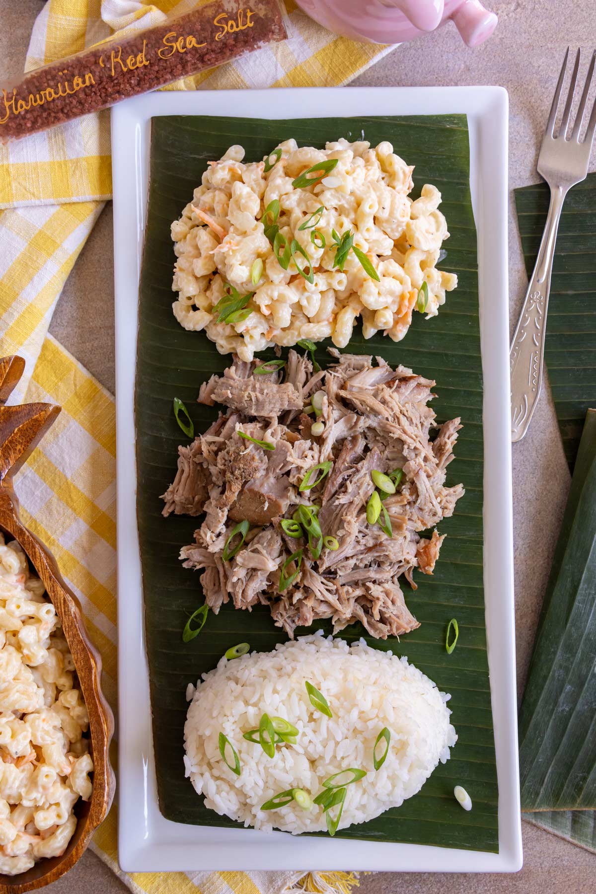 A banana leaf topped with homemade kalua pork, white rice, and Hawaiian mac salad.