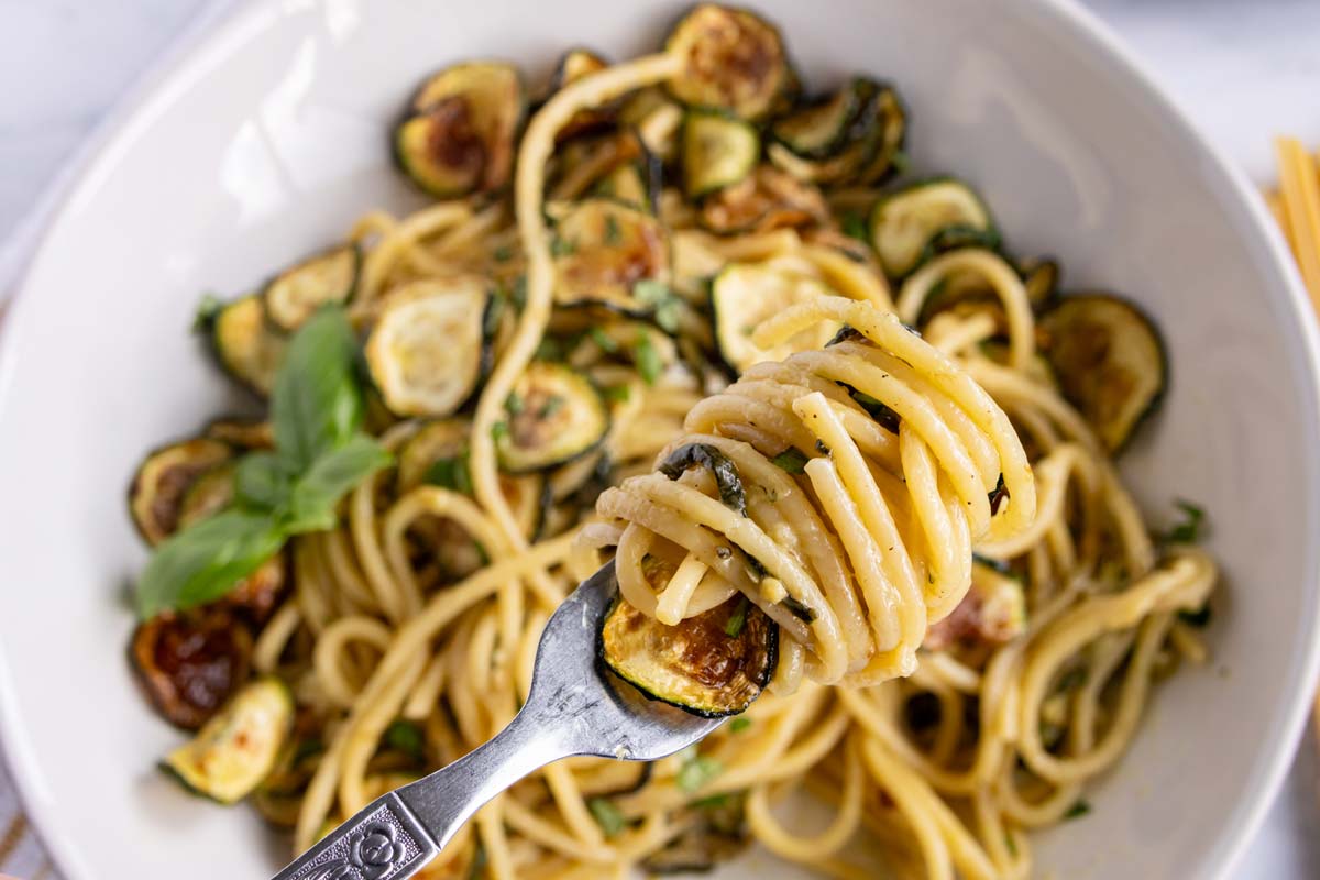 Cheesy spaghetti alla nerano with fried zucchini twirled around a fork.