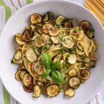 Spaghetti alla nerano topped with fried zucchini coins and a sprig of fresh basil.