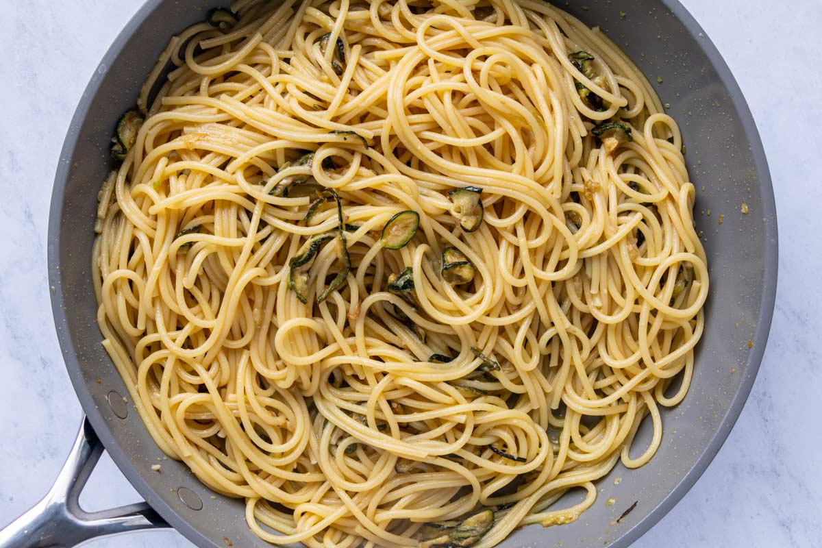 Spaghetti tossed with fried zucchini in a nonstick skillet.