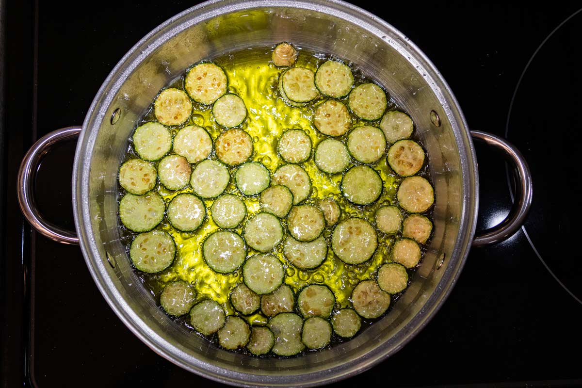 Slices of zucchini starting to brown as they fry in hot oil.