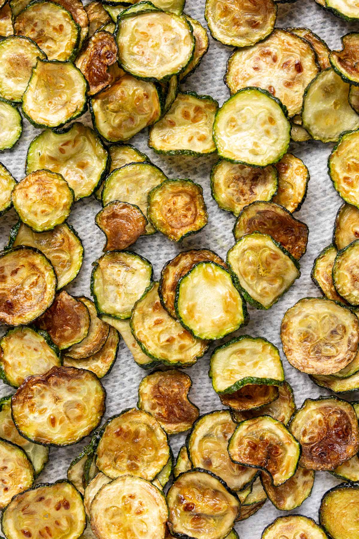 Crispy and browned zucchini coins on a paper towel lined surface.