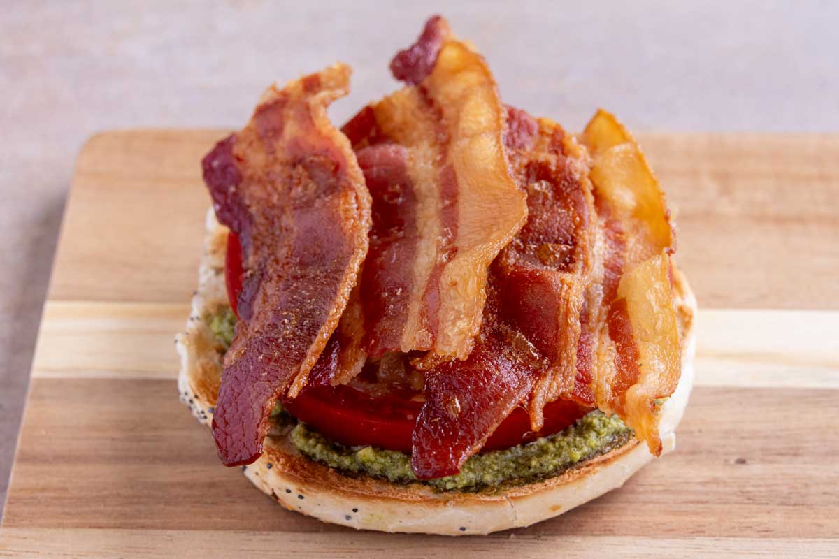 Crispy bacon added to the bottom of a breakfast bagel sandwich.