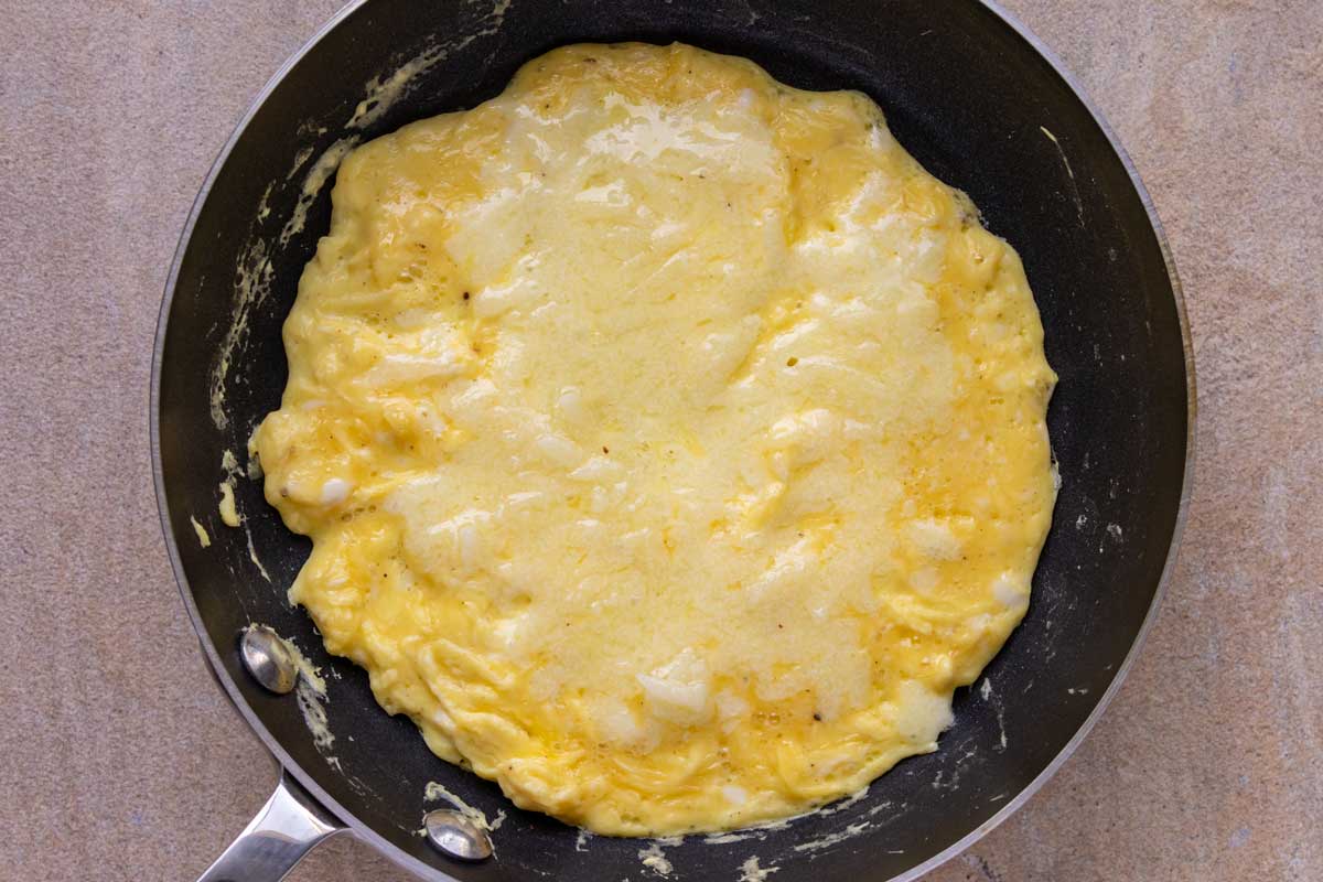 A simple omelet in a nonstick frying pan topped with melted manchego cheese.